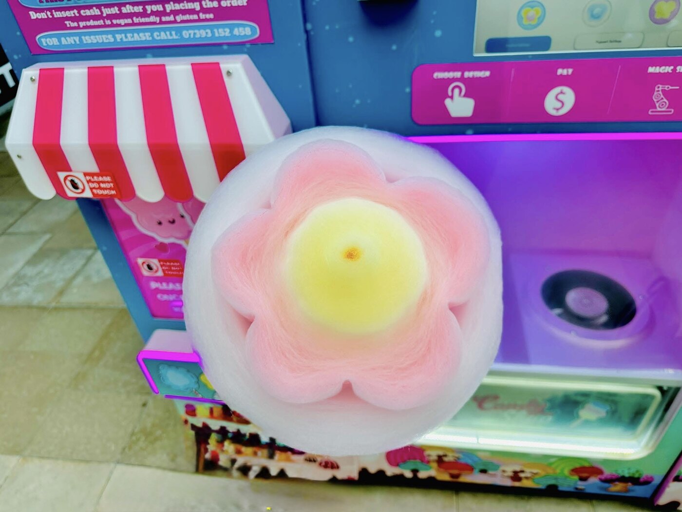 Freshly made pink and yellow flower-shaped candy floss in front of our vending machine